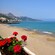 Flowers in a pot overlook a sprawling shoreline in the beach town of Giardini Naxos